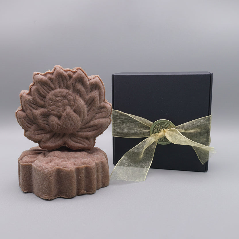 Dark pink Shampoo Bar sitting next to a black box with gold ribbon
