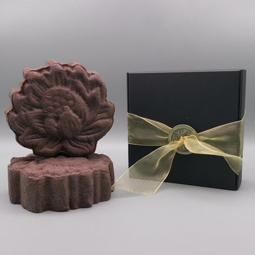 purple alkanet shampoo bar sitting next to a black box with gold ribbon