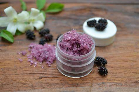 Container of beautiful purple sugar scrub next to luscious black raspberries | Okoboji Soap Company